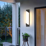 Minimalist linear wall light outdoor featuring glass shade chandelier design creating dramatic uplighting and downlighting on neutral wall.