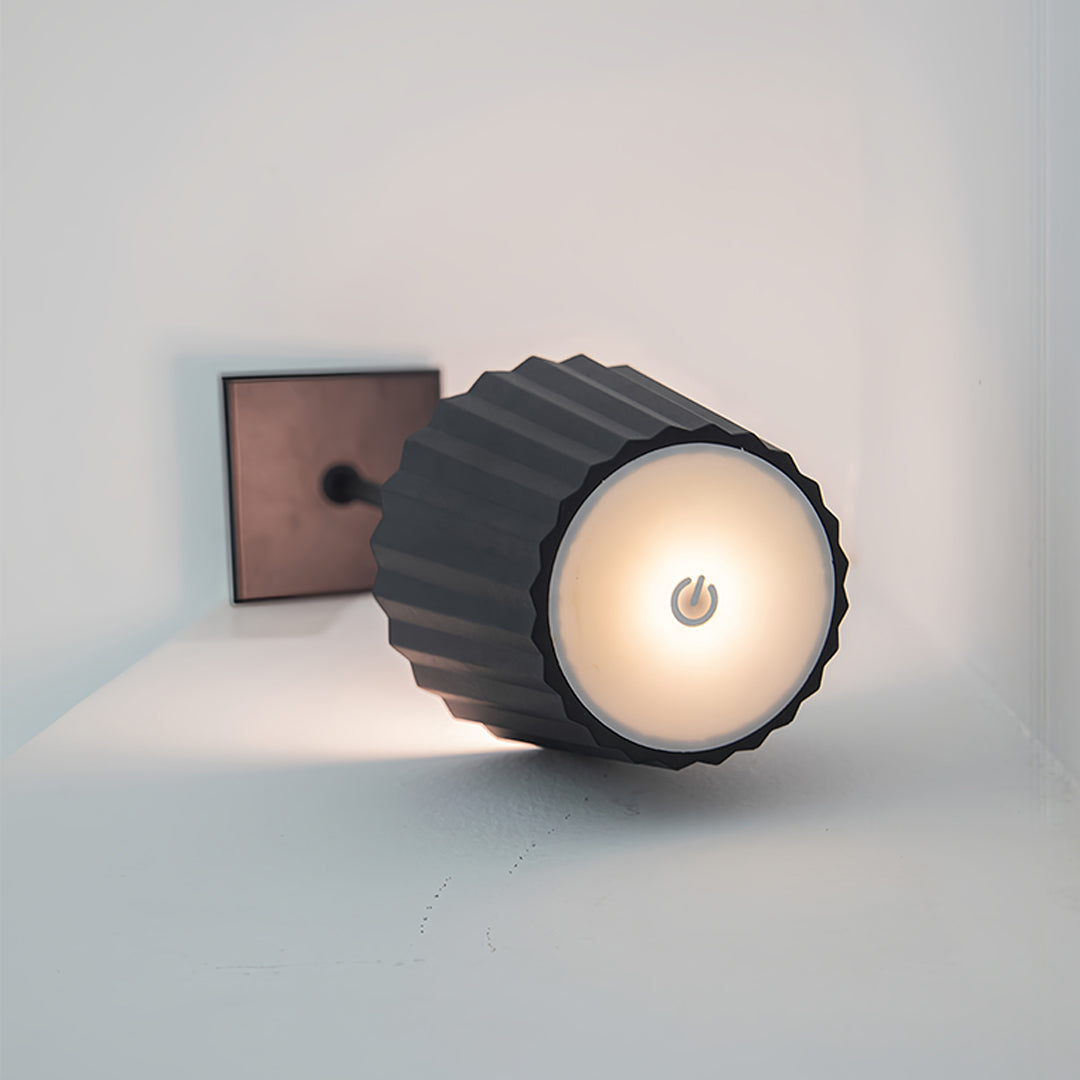 Minimalist modern metal table lamp creating focused illumination on wooden surface in dark interior