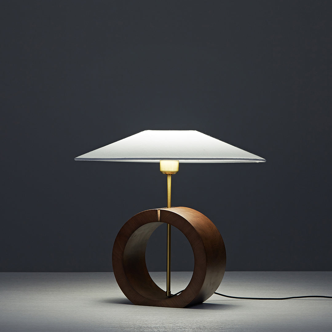 Minimalist natural wood table lamp glowing softly in dark background.