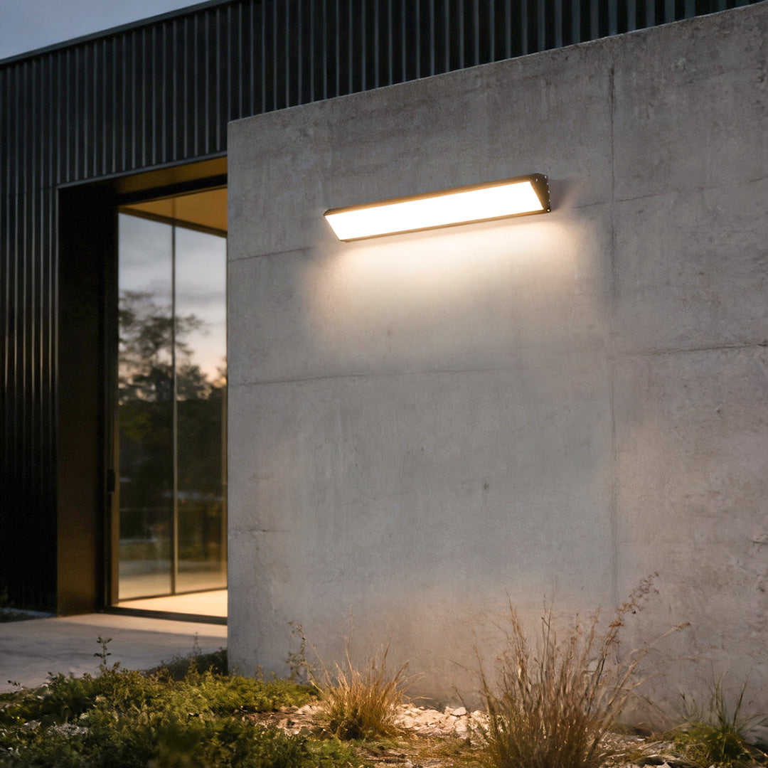 Minimalist outdoor wall sconce light installed on a concrete facade near an entryway.