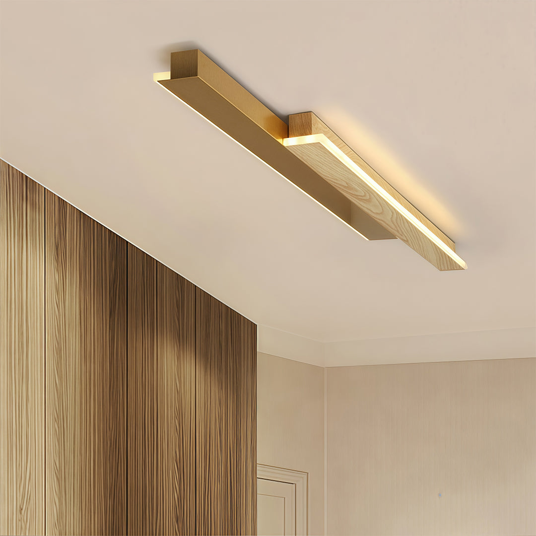 Minimalist overlapping linear led wall light fixture in gold and wood, installed as a modern ceiling light in a hallway.