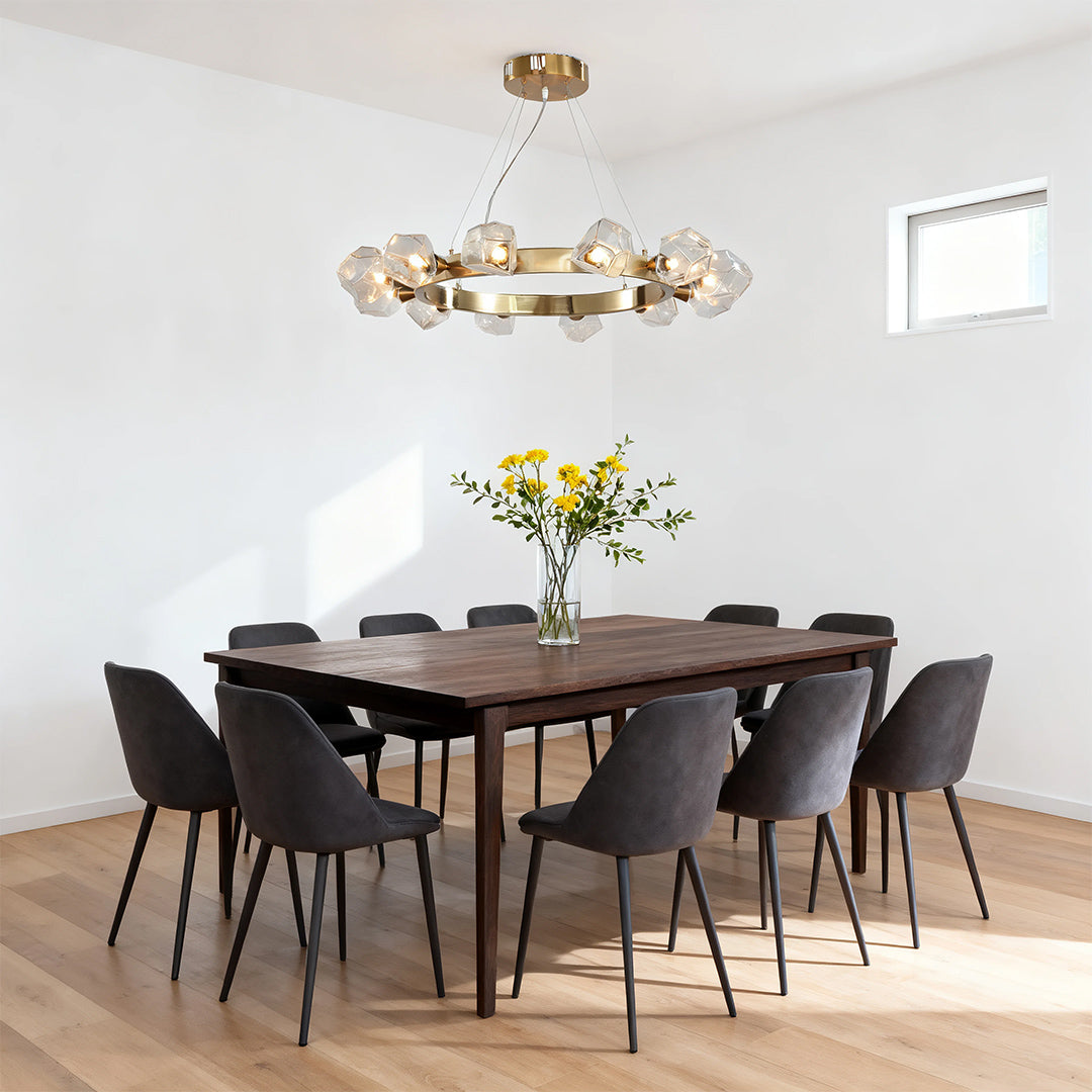 Modern minimalist dining room featuring a gold round chandelier with sculptural glass accents over a dark wood rectangular table.