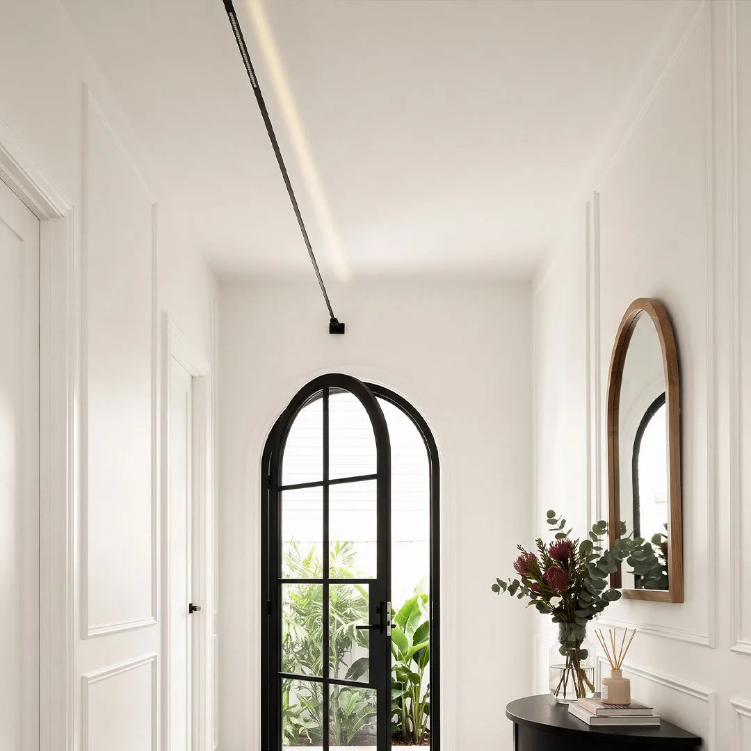 Minimalist skyline linear LED lighting running across a hallway ceiling beside an arched mirror and entry console.