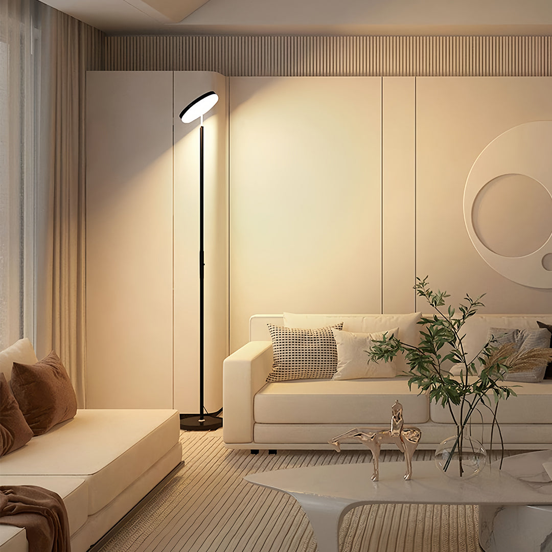 Modern uplight floor lamp with sleek black pole and circular LED top providing ambient ceiling illumination