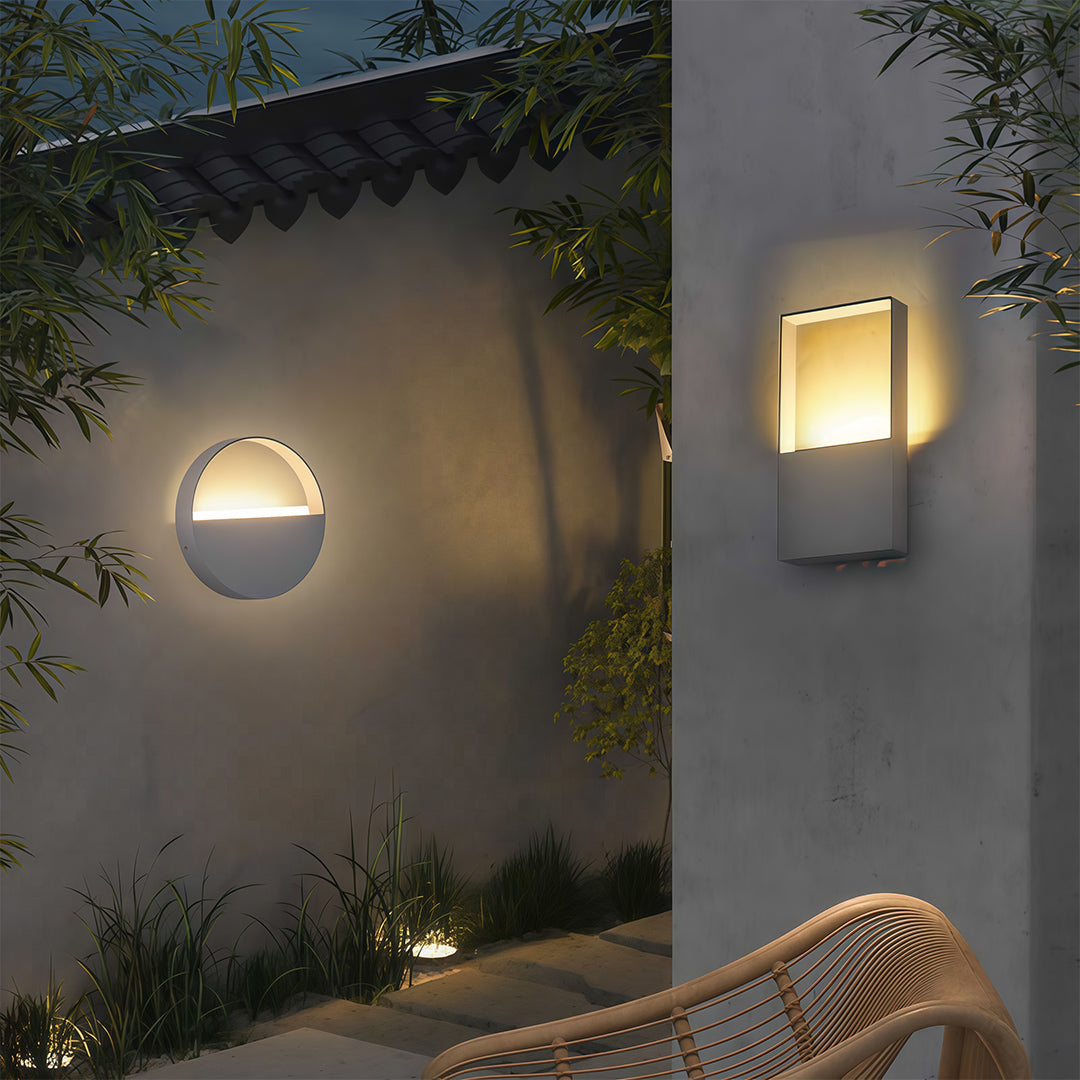 Minimalist wall mount exterior light featuring glass shade chandelier aesthetic illuminating contemporary concrete outdoor wall.