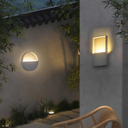 Minimalist wall mount exterior light featuring glass shade chandelier aesthetic illuminating contemporary concrete outdoor wall.