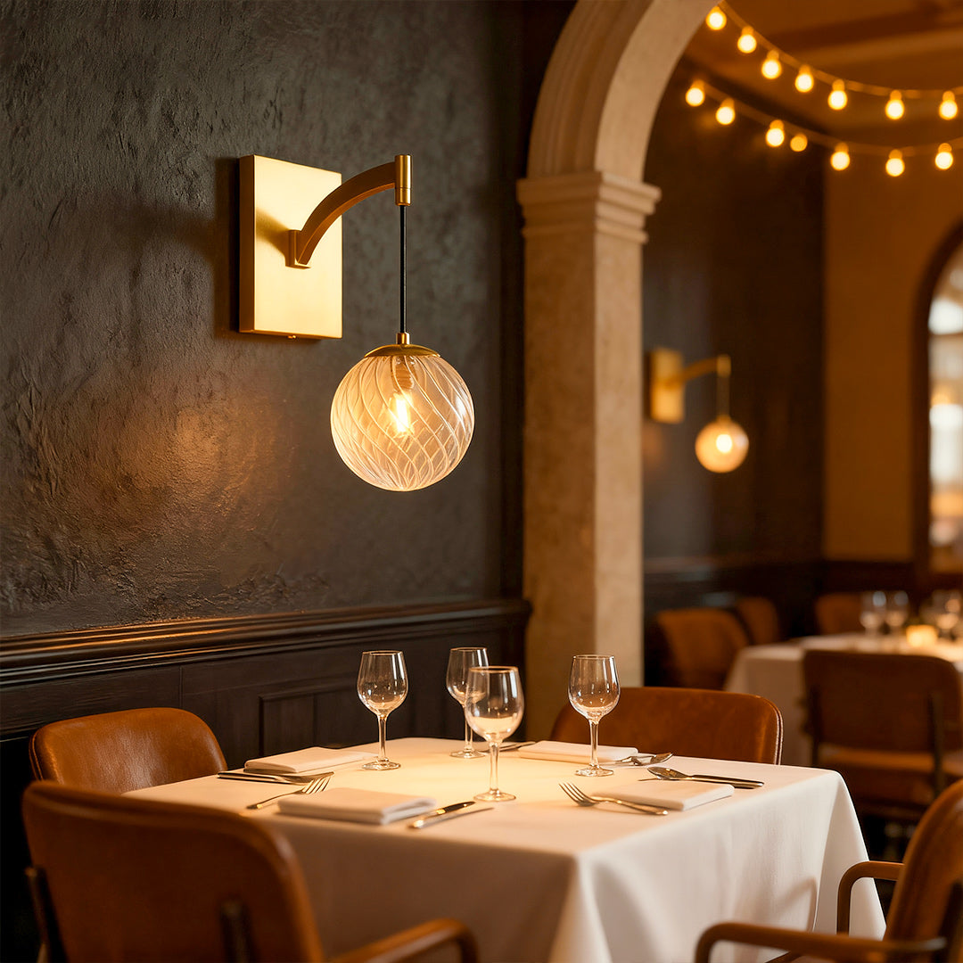 Minimalist wall mounted pendant light featuring glass shade chandelier design providing ambient lighting in elegant restaurant setting.