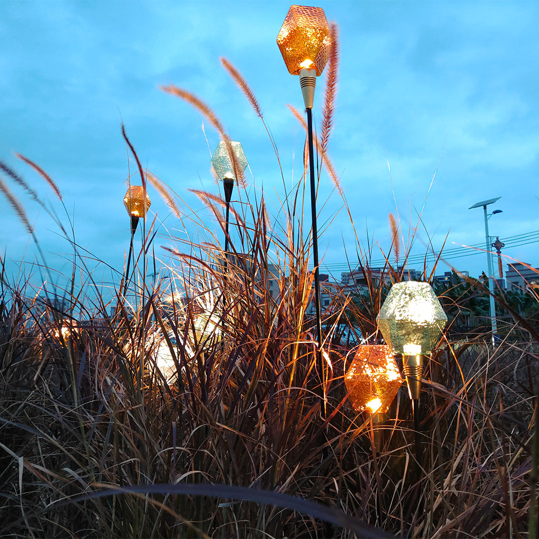 Golden and amber garden globe stakes producing warm illumination for decorative landscape lighting pathway.