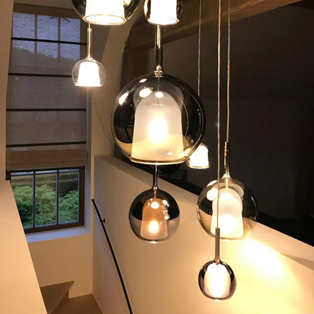Mixed metal glass ball pendant lights installation over contemporary staircase