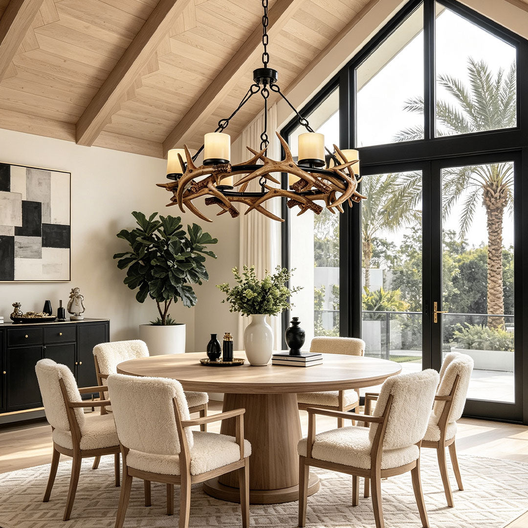 Modern antler chandelier hanging above a dining table in a bright contemporary cabin space.
