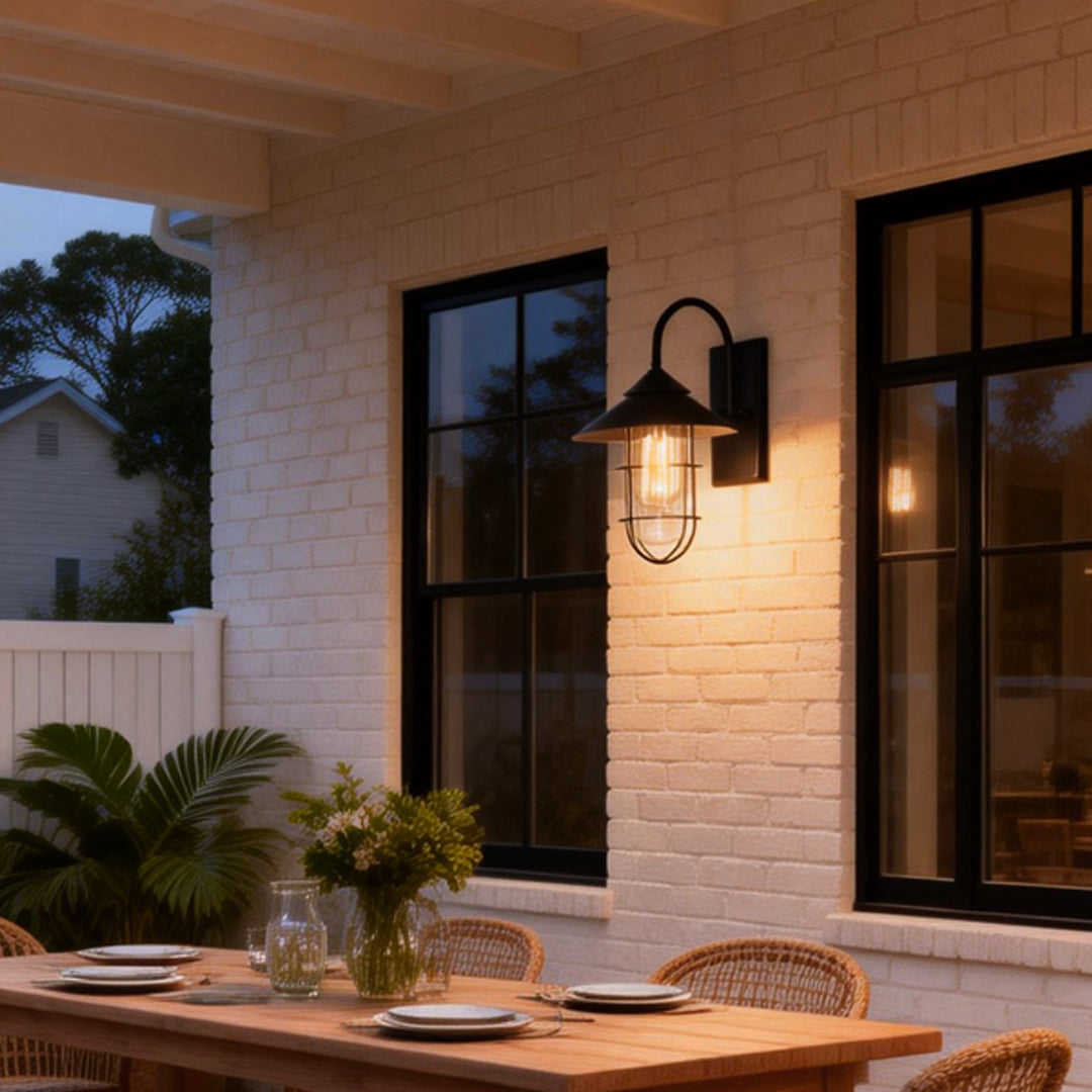 Modern barn wall light with black metal frame and clear glass, mounted beside a white exterior wall.