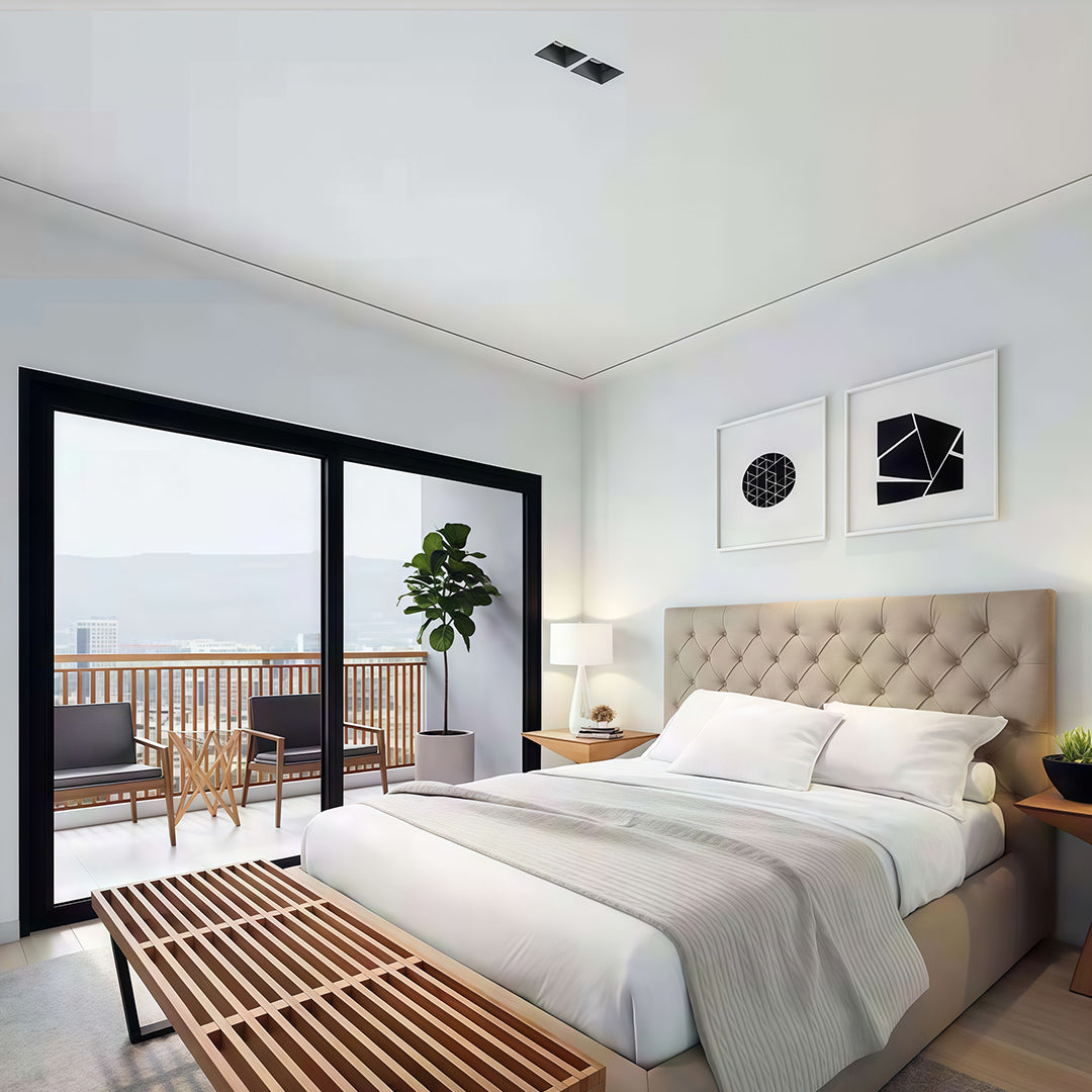 Bright modern bedroom with a balcony, featuring discreet black square led downlights on a white ceiling.