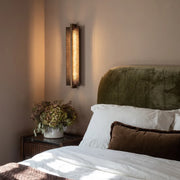Modern bedroom with vertical wall sconce warm bedside lighting and neutral decor