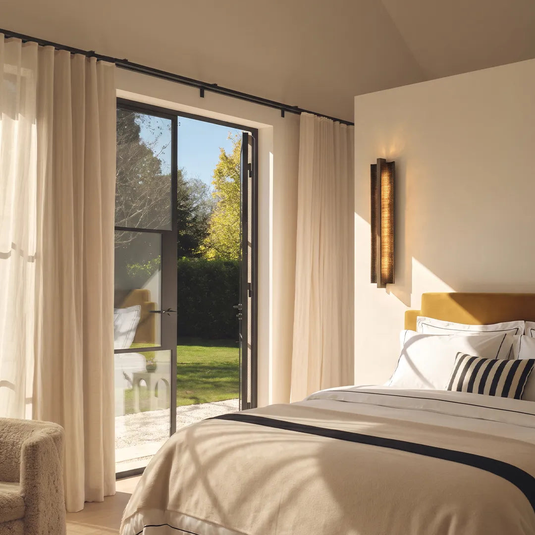 Modern bedroom with vertical wall sconce large window and warm neutral interior