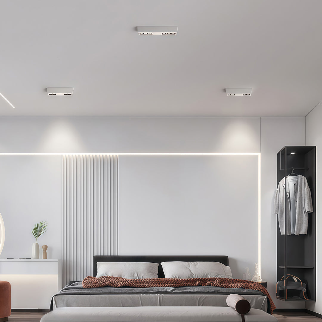 Modern bedroom ceiling featuring white surface-mounted square downlights fixtures and linear accent lighting.