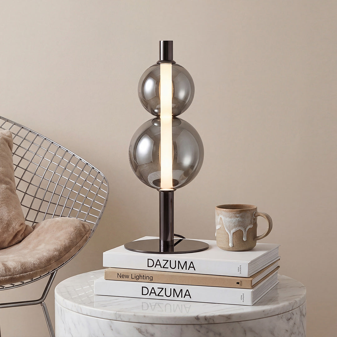 Modern black Art Table Lamp with two stacked smoke grey glass spheres on a white marble table.