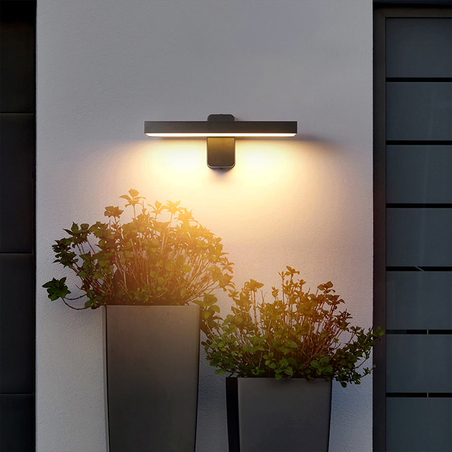 Modern black and gold wall sconce creating warm accent lighting in contemporary interior
