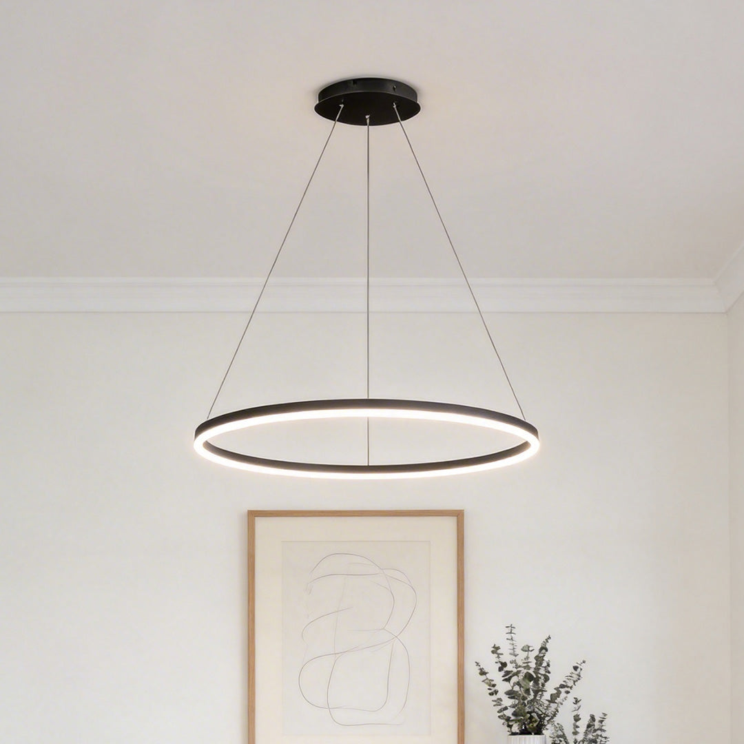 Modern black LED ring chandelier hanging in a minimalist living room above a framed art piece ok