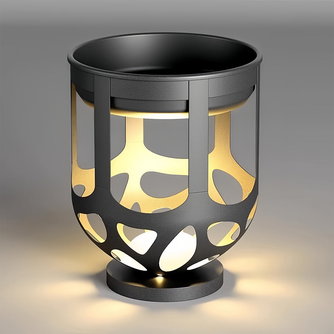 Modern black lighted outdoor planter with intricate cutout patterns, illuminated against a grey background.