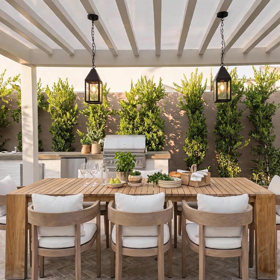 Modern black outdoor pendant lights hanging above an outdoor dining table beneath a pergola in a stylish backyard setting.