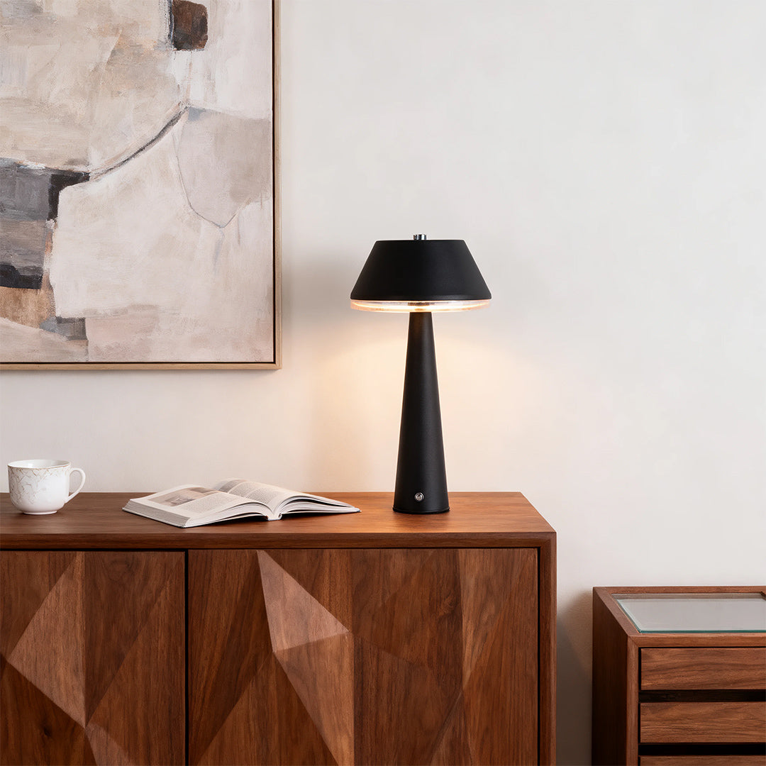 Modern black rechargeable table lamps casting warm light on a wooden console cabinet in a minimalist living space. 