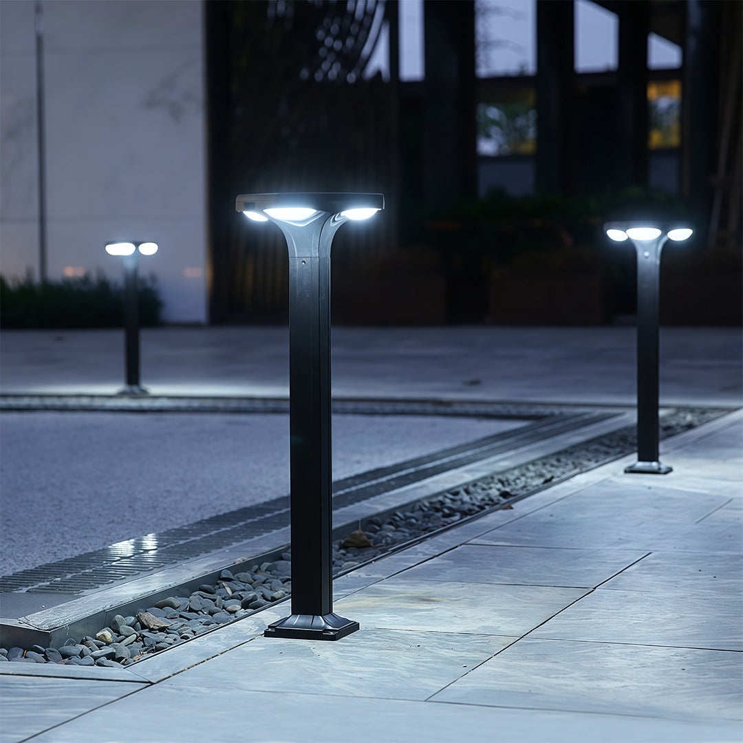 Modern black outdoor wall light with a subtle design, casting light across a garden path.