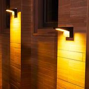 Modern wall mount outdoor light fixtures in a black finish casting warm downlight on a tiled exterior wall.