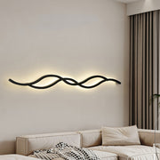 Modern black wavy bedside wall light fixture providing soft accent lighting in a minimalist bedroom setting.