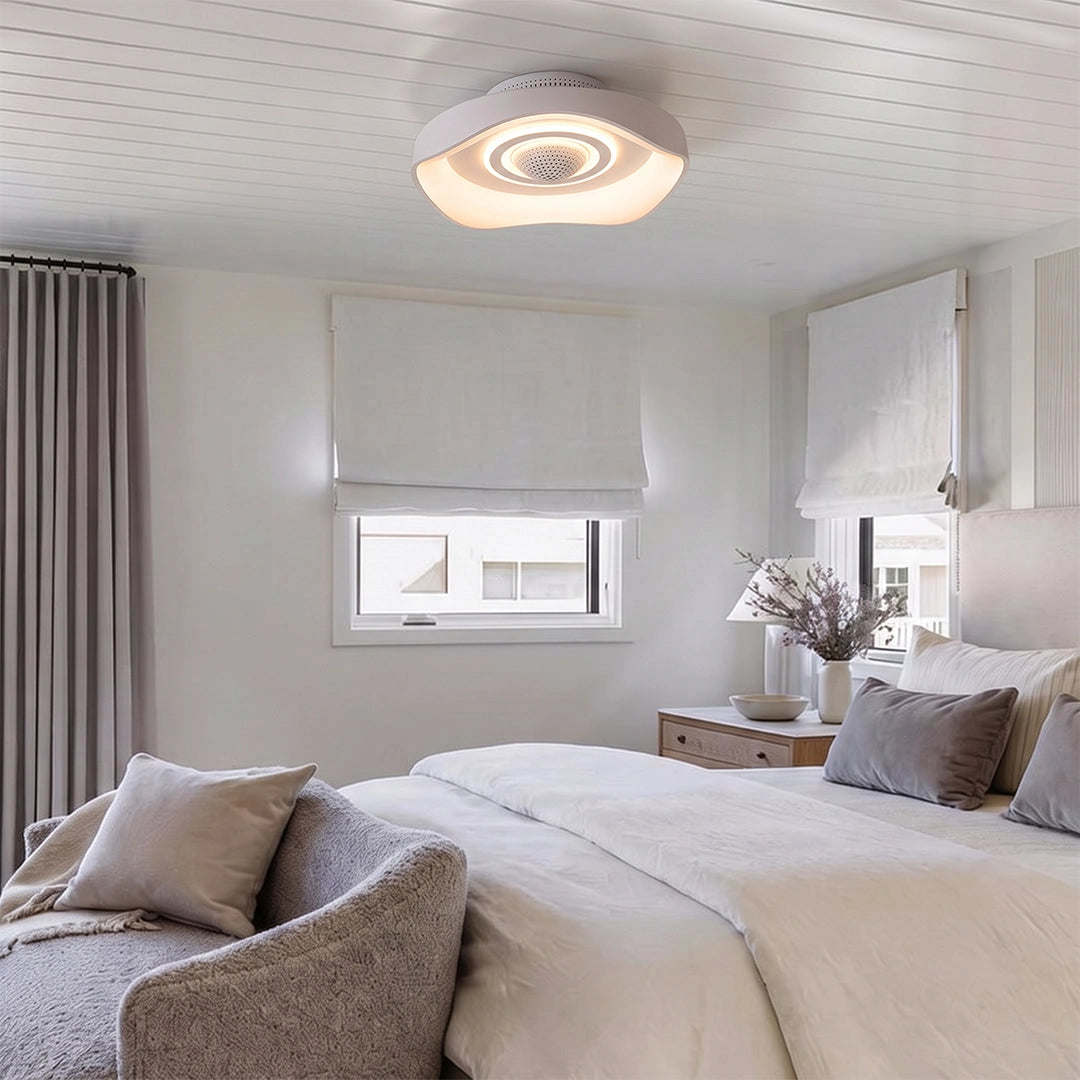 White bladeless fan with light installed on the ceiling of a bright modern bedroom with warm ambient lighting.