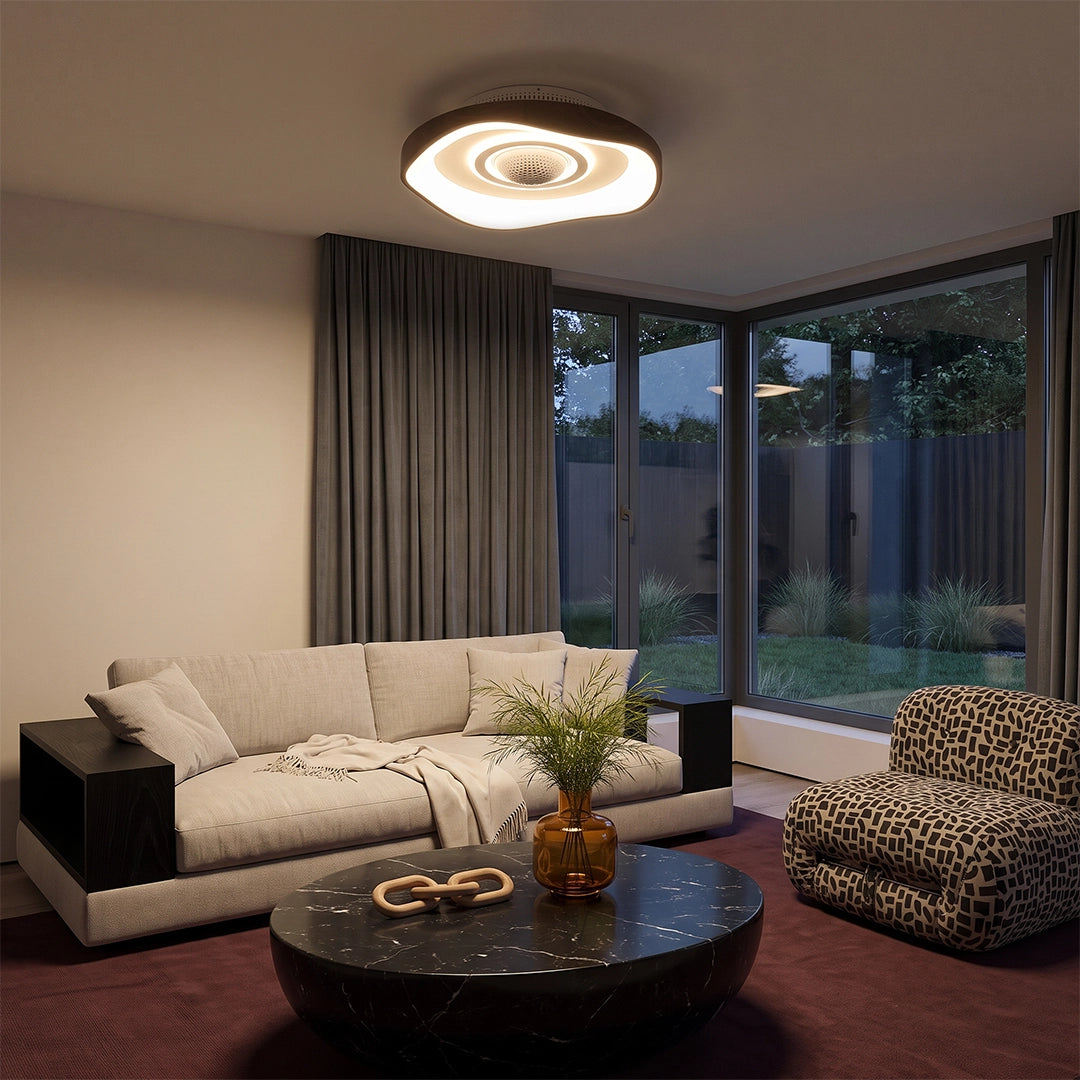 Contemporary bladeless fan with light on a living room ceiling, illuminating a modern seating area with large windows.