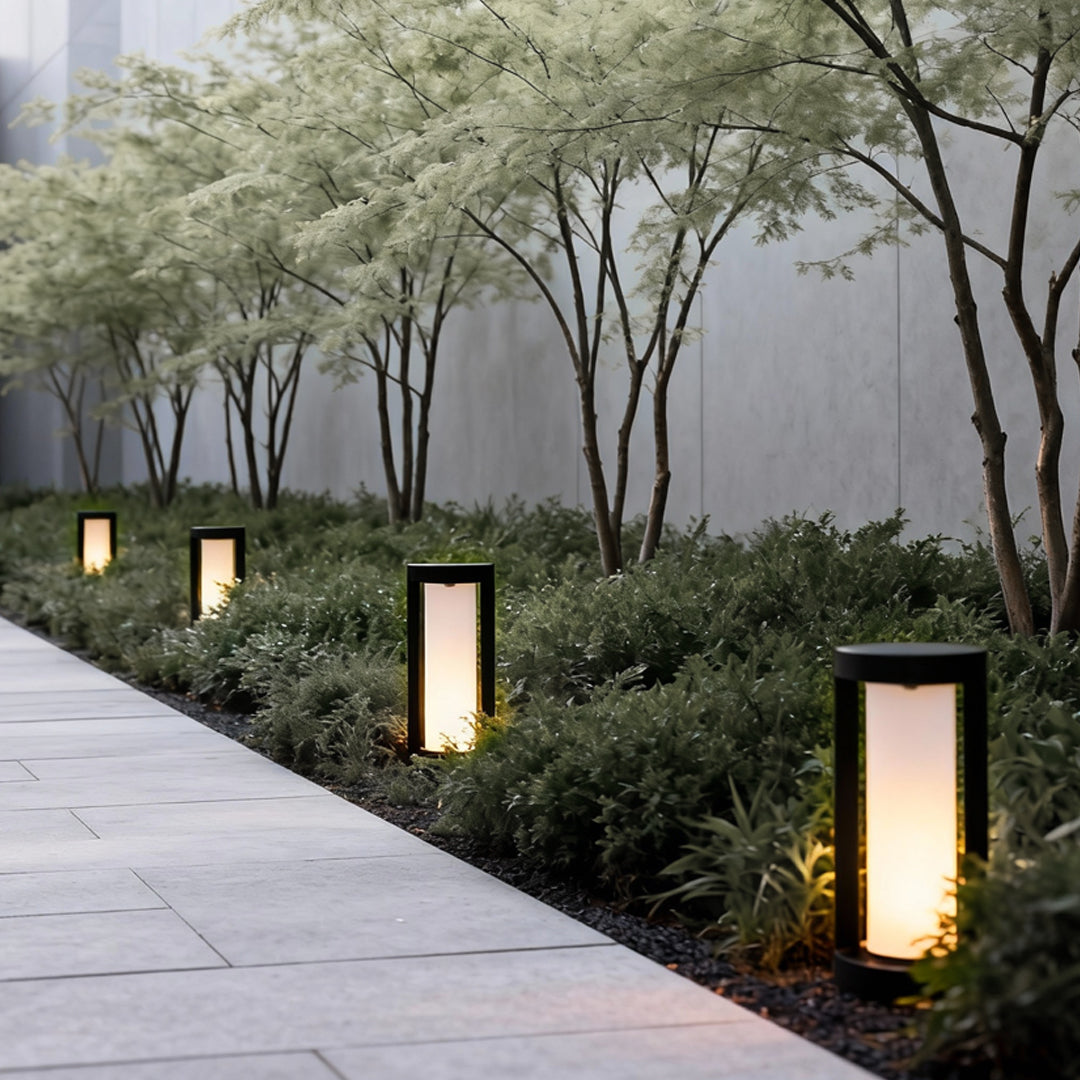 Modern bollard landscape light providing soft illumination along a landscaped garden walkway.
