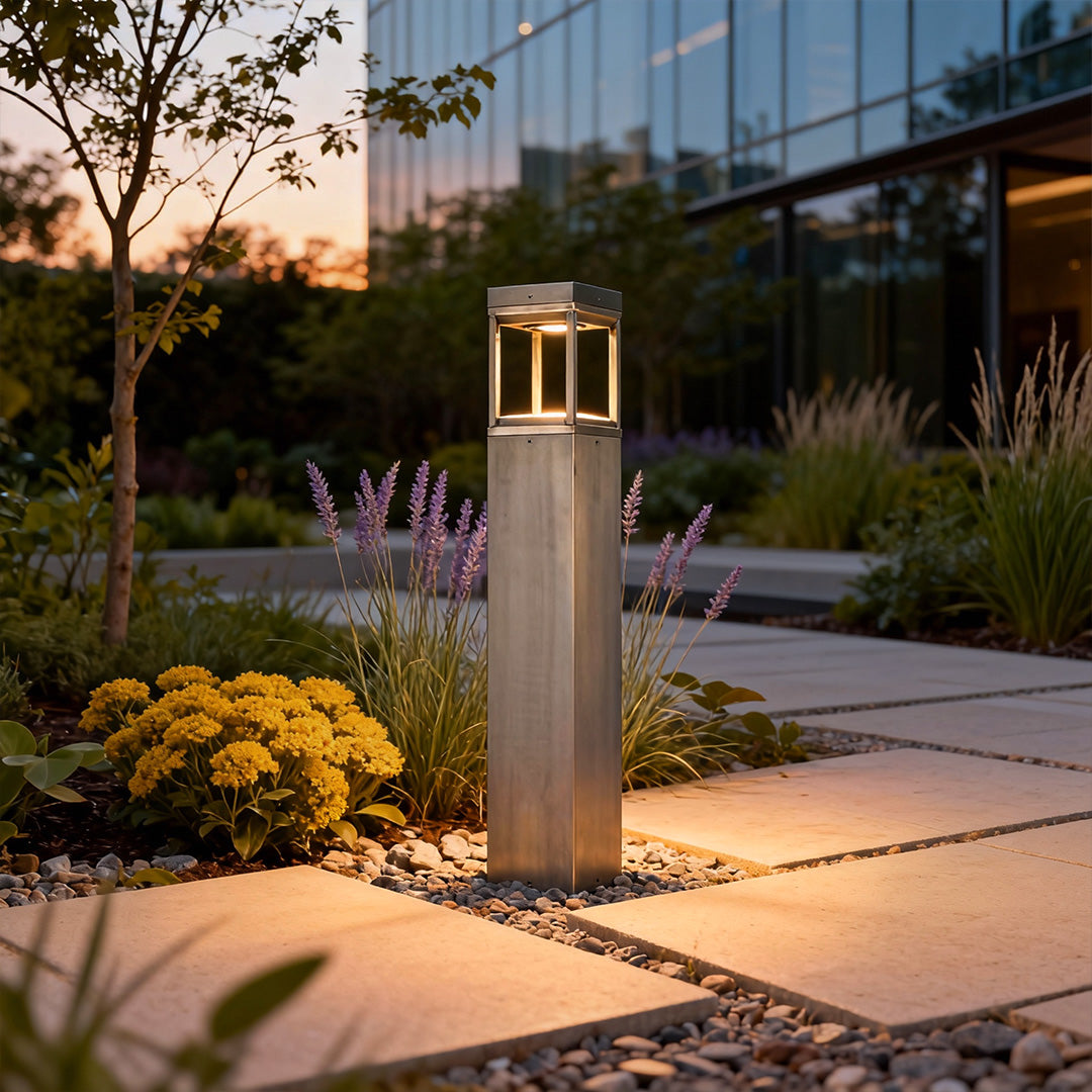 Modern bollard light installed along a landscaped garden path, providing subtle illumination and a sleek architectural look.