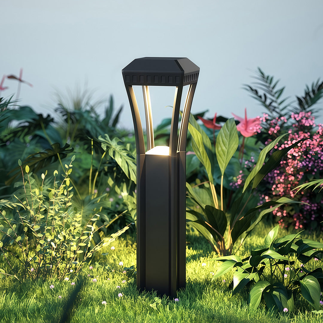 Modern bollard light installed in a garden, providing warm illumination along a landscaped pathway.