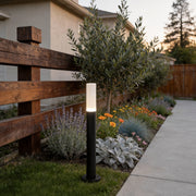 Modern bollard lighting illuminating a garden pathway with a sleek cylindrical design.