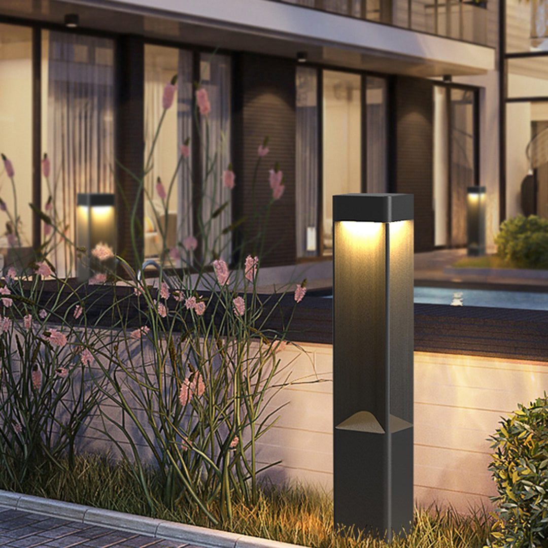 Modern bollard lighting on a patio pool area next to the contemporary house exterior at night.