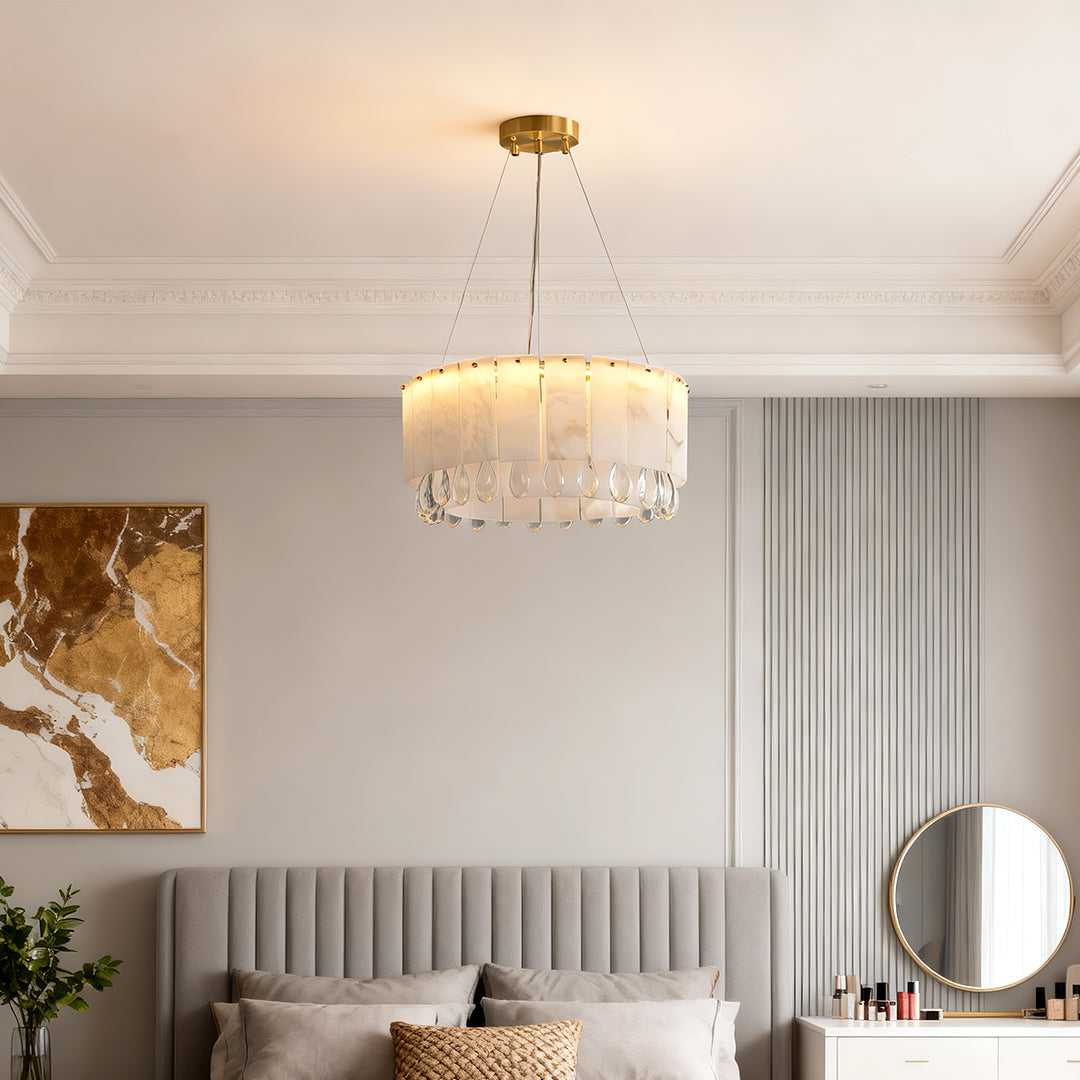 Warm brass chandelier suspended above a modern bed with wall art.