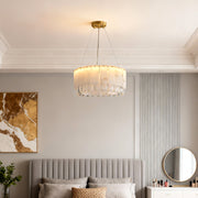 Warm brass chandelier suspended above a modern bed with wall art.