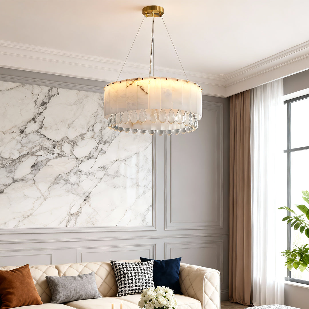 Modern brass chandelier hanging in bedroom with marble wall and neutral decor.