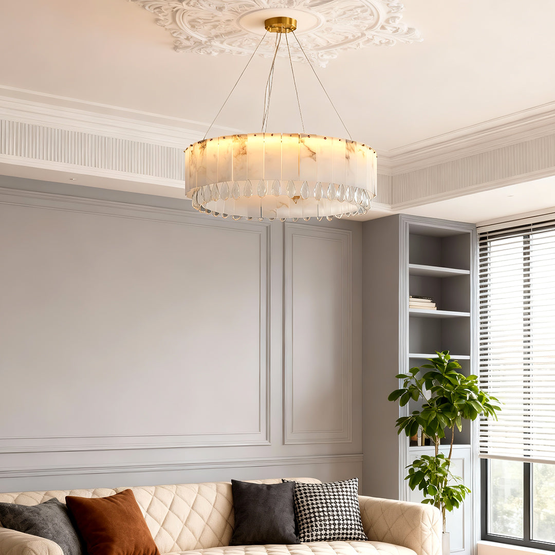 Modern brass chandelier lighting up a chic living room with sofa and molding ceiling.