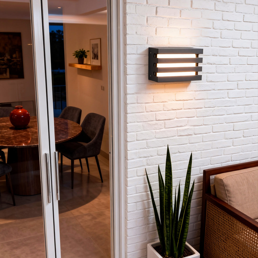 Modern outdoor wall lights LED mounted beside a door, casting even warm light on a white brick wall.