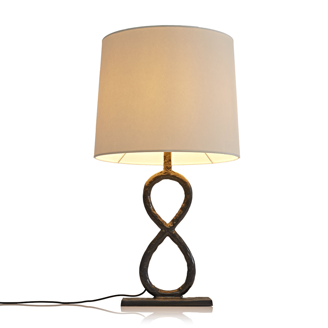 Modern bronze metal table lamp with white linen shade and artistic looped base.