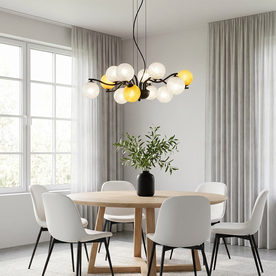 Modern bubble chandelier with mixed glass globes hanging over a round dining table in a bright minimalist space.
