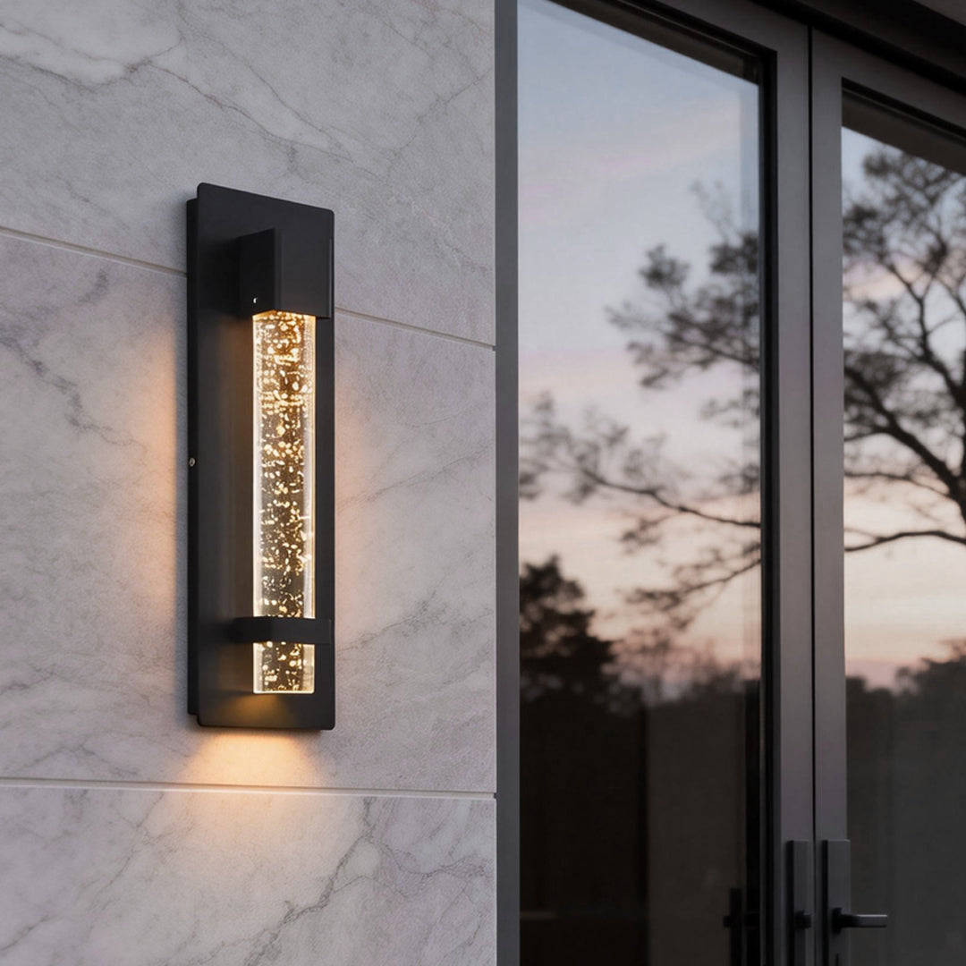 Modern bubble wall sconce mounted beside glass door, creating warm vertical light accents on contemporary exterior wall.