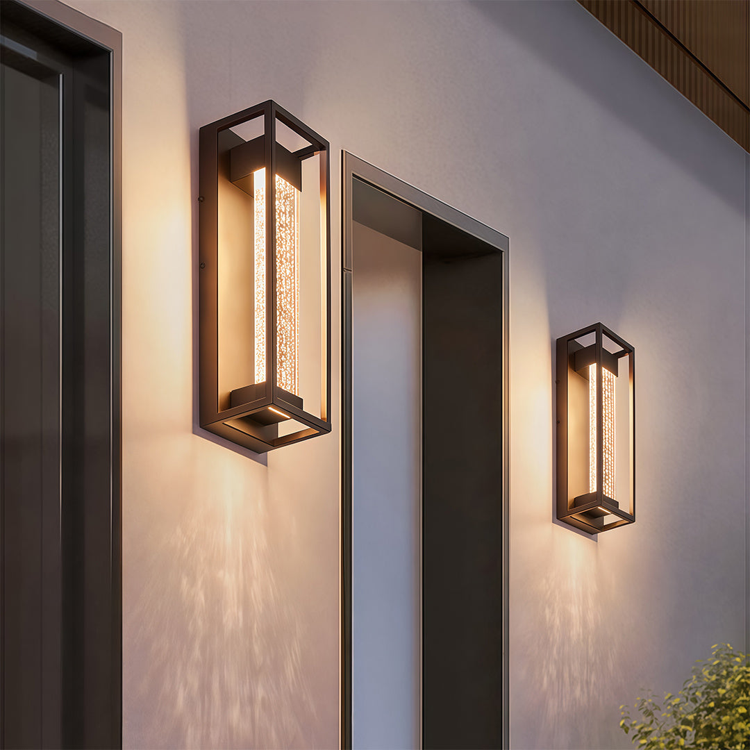 Outdoor sconces black with a textured glass front, mounted beside a modern building entrance.