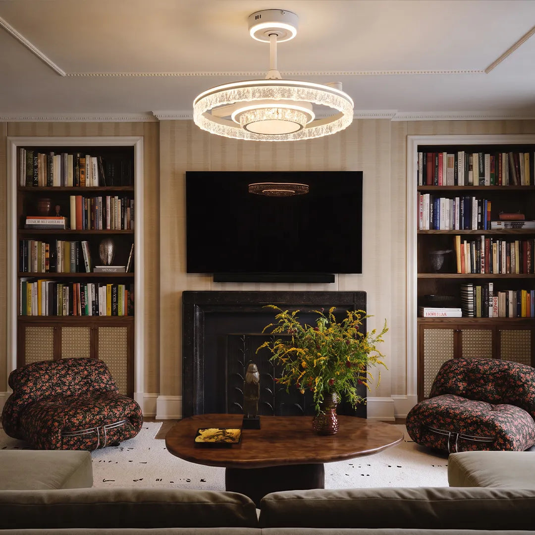 Modern ceiling fan with lights hanging above a cozy living room with built-in shelves and a fireplace.