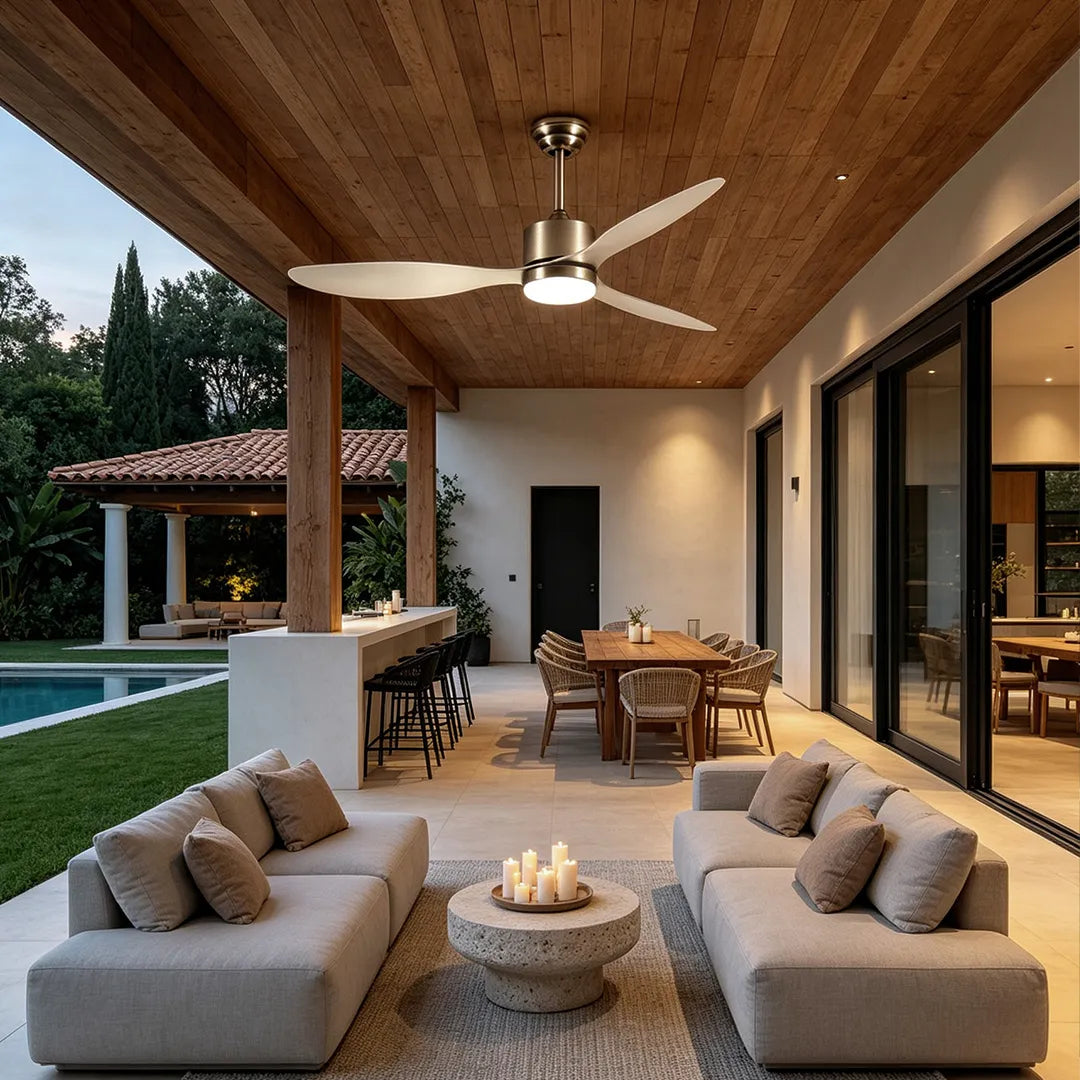 Modern ceiling fans with LED lights above a covered outdoor living area with sectional seating and a dining table.