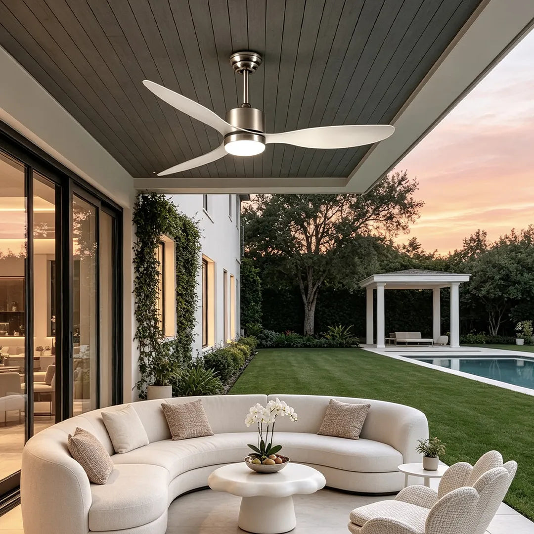 Modern ceiling fans with LED lights mounted on a gray porch ceiling above a curved outdoor sofa at sunset.