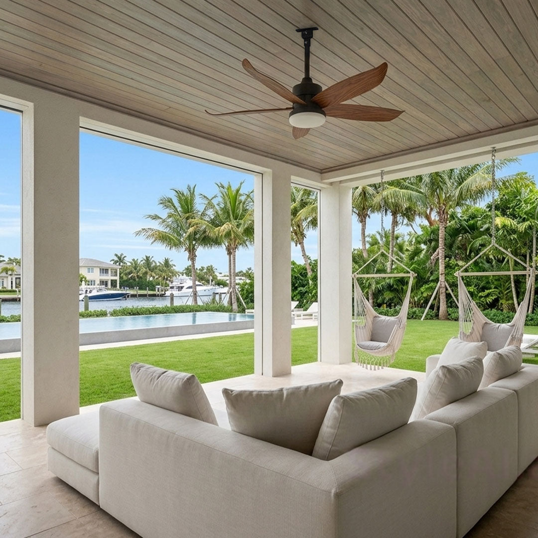 Modern ceiling fans with lighting installed on a covered outdoor lounge overlooking a waterfront landscape.
