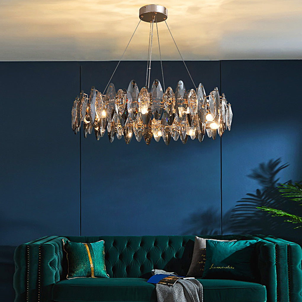 Modern chandelier with crystals over a green velvet sofa against a deep blue paneled wall.