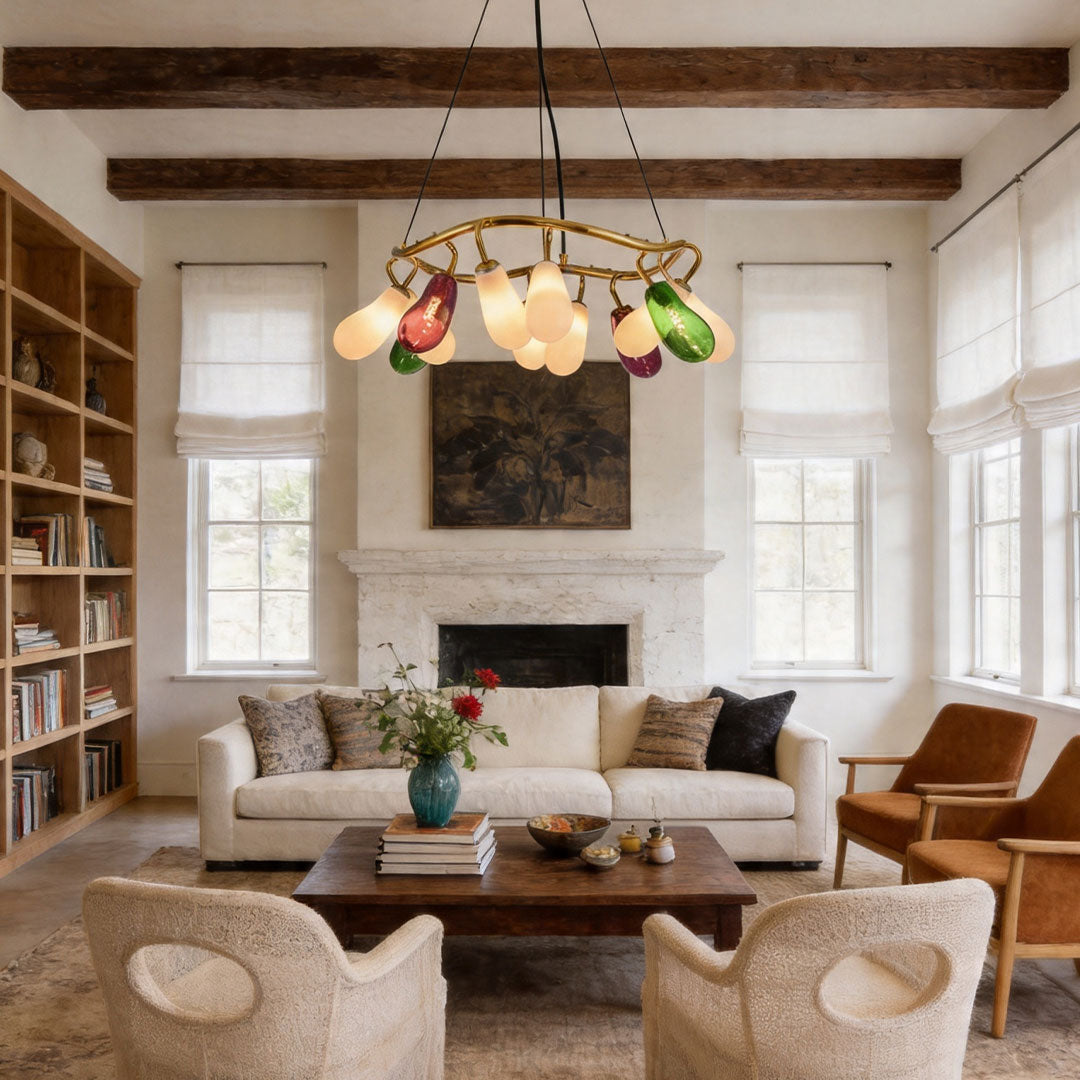 Modern large chandelier with mixed color glass lights in a warm living room with wooden ceiling beams.
